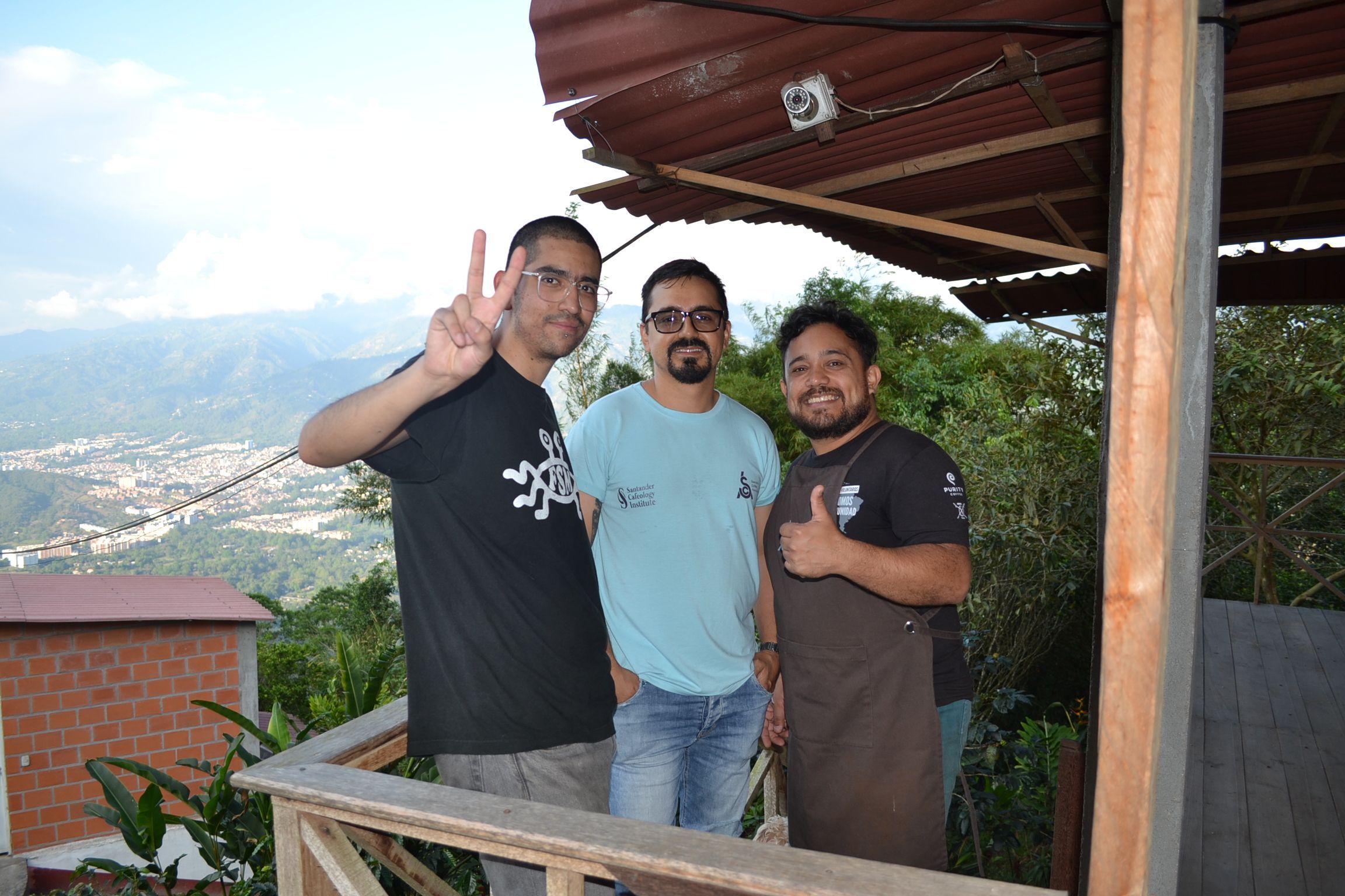 Three people on a terrace at Finca San Fernando, with mountains and a valley town behind them